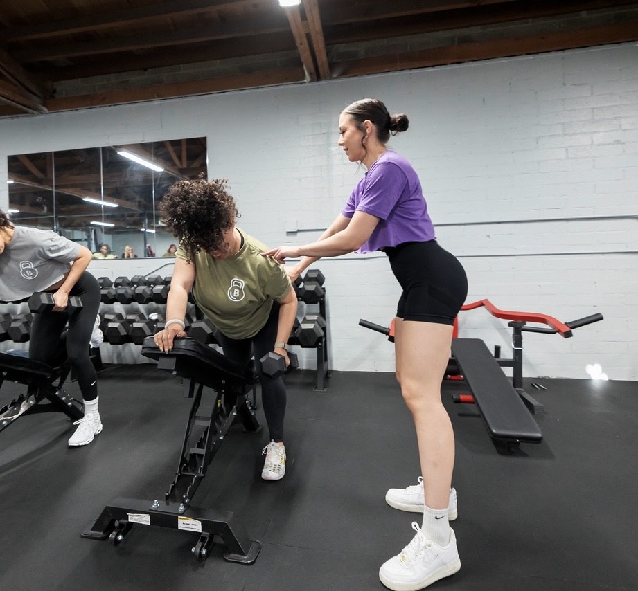 Beth coaching a client through one arm dumbbell rows on an incline bench